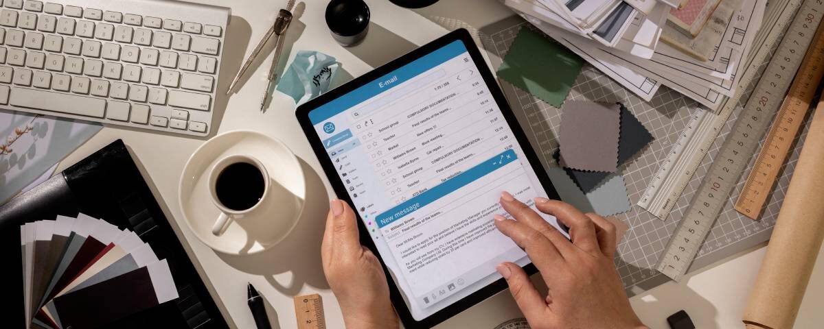 Przedsiębiorca potwierdzający wysyłkę faktury na tablecie obok laptopa