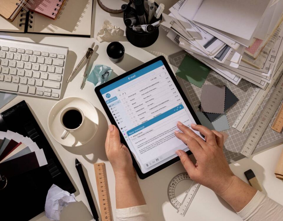 Przedsiębiorca potwierdzający wysyłkę faktury na tablecie obok laptopa