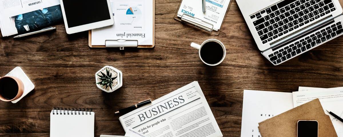 Widok z góry na biurko z laptopem i dokumentami w różnych językach symbolizującymi globalną współpracę