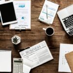 Widok z góry na biurko z laptopem i dokumentami w różnych językach symbolizującymi globalną współpracę