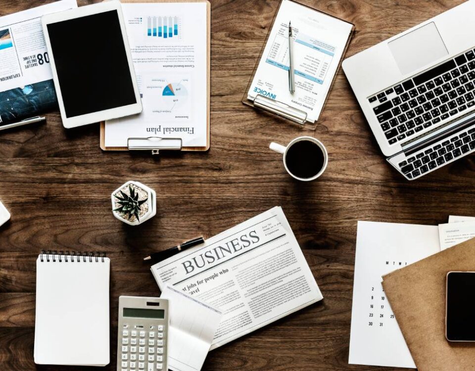 Widok z góry na biurko z laptopem i dokumentami w różnych językach symbolizującymi globalną współpracę