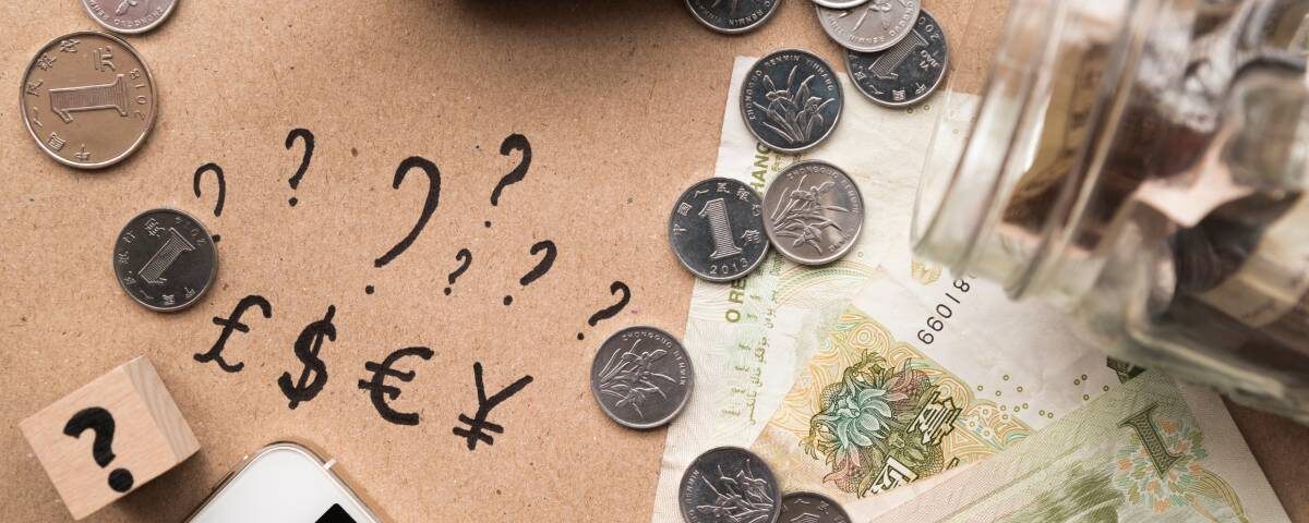 Widok z góry na biurko z pieniędzmi w róznych walutach, dokumentami i kalkulatorem używanymi do przeliczania kursów walut