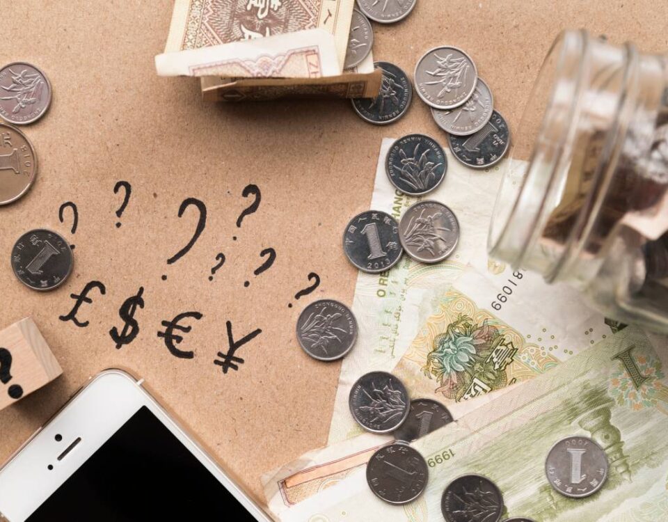 Widok z góry na biurko z pieniędzmi w róznych walutach, dokumentami i kalkulatorem używanymi do przeliczania kursów walut