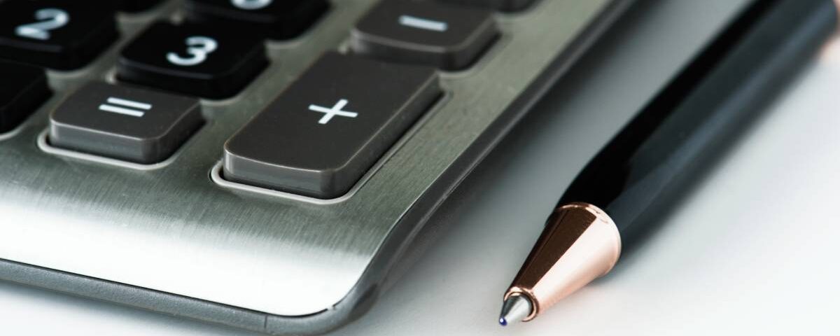 Zbliżenie na kalkulator i długopis symbolizujące analizę podatkową ukrytych zysków w estońskim CIT