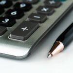 Zbliżenie na kalkulator i długopis symbolizujące analizę podatkową ukrytych zysków w estońskim CIT