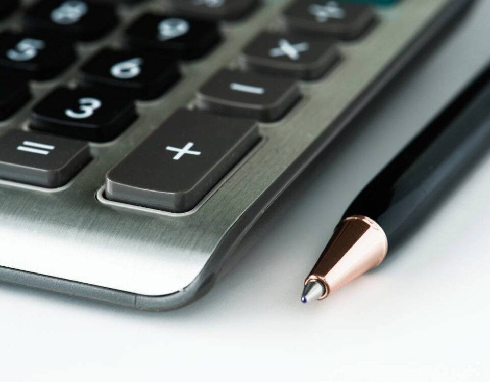 Zbliżenie na kalkulator i długopis symbolizujące analizę podatkową ukrytych zysków w estońskim CIT